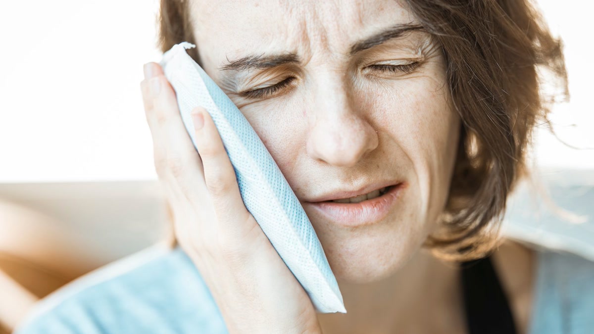 Woman holding her cheek from wisdom tooth pain.